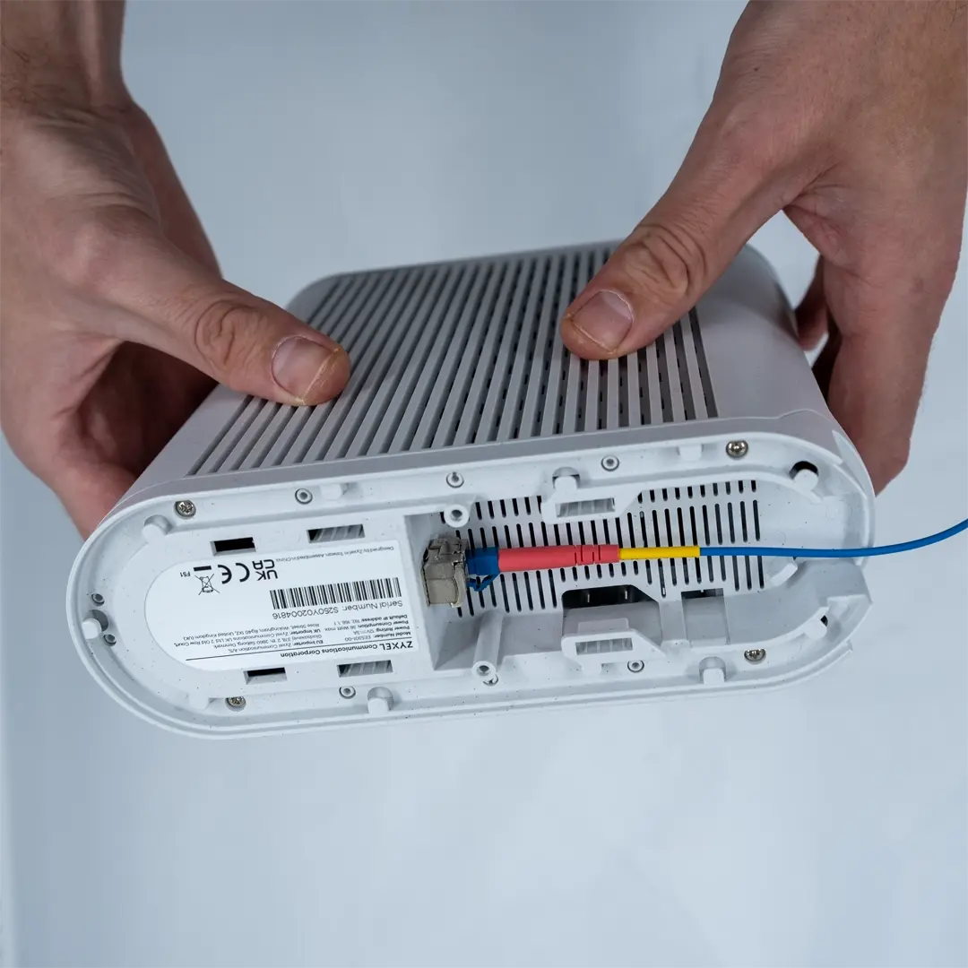 En person holder en router og viser det blå fiberkabel, som skal tilsluttes fiberstikket i boligen.